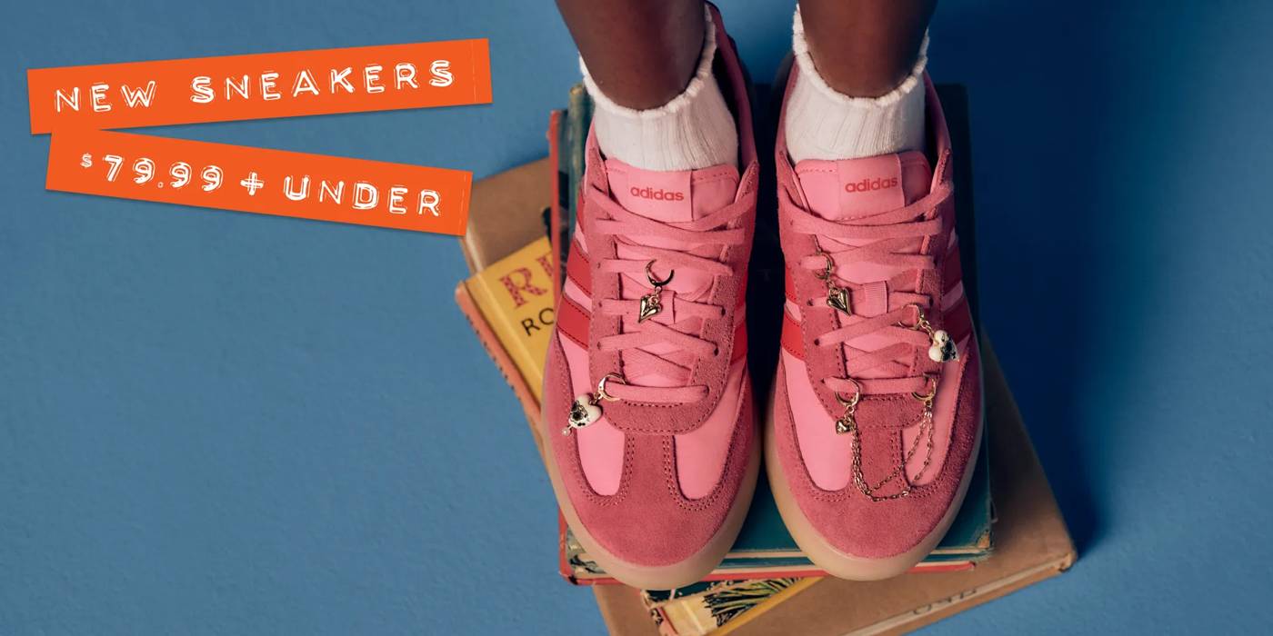 Pink adidas sneakers with charms, on top of a stack of books.