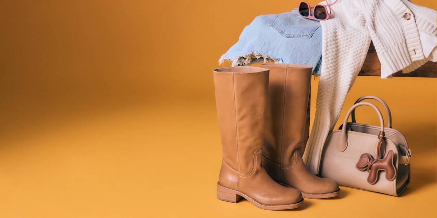 Featuring a pair of brown tall boots styled with a matching handbag and outfit.