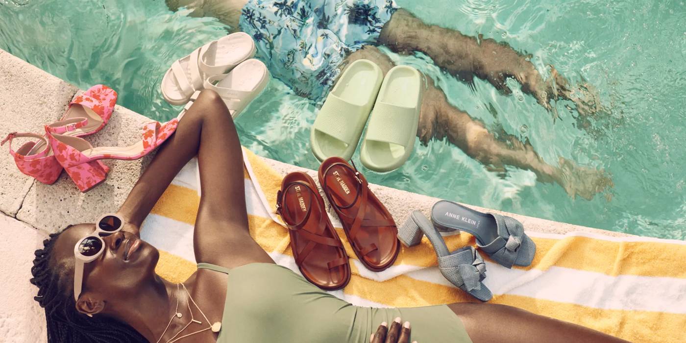 Featuring a woman next to a pool with sandals all around her. Click to shop sandals.